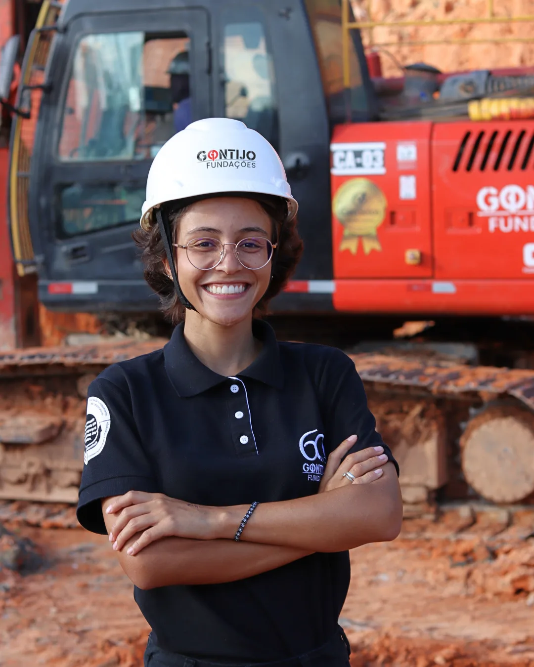 Colaboradora da Gontijo Fundações em obra, vestindo capacete e camisa dos 60 anos