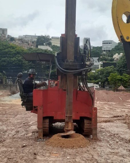 Opoerador em máquina do tipo tyrado mecanizado realizando furo no solo. Máquina vermelha nas cores da empresa Gontijo Fundações.